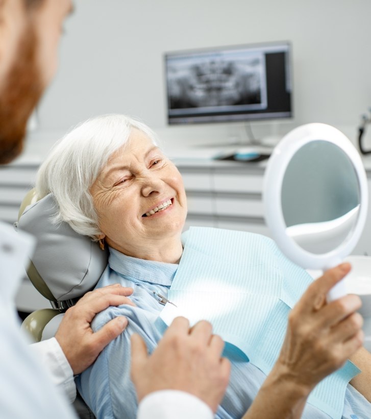Senior dental patient admiring her smile in a mirror