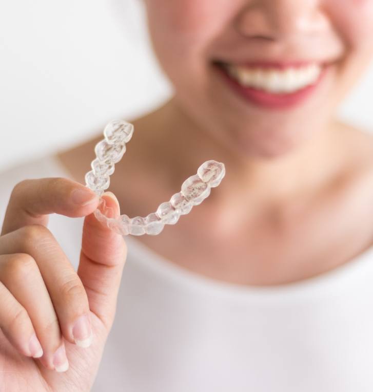 Smiling person holding Invisalign tray