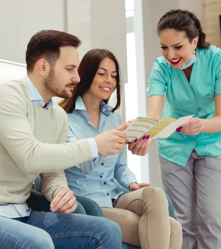 Dental team member showing a pamphlet to two patients