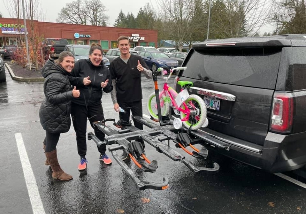 Team members attaching a kids bicycle to the back of a car