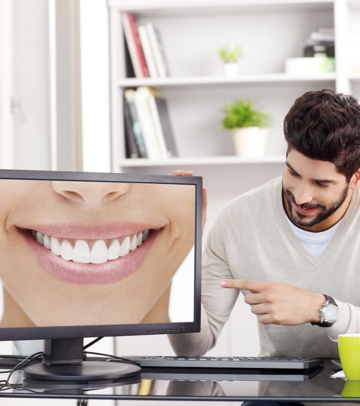 Man pointing to computer monitor showing close up of smile with straight white teeth