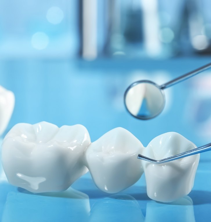 Close up of dental bridge on desk next to dental mirror