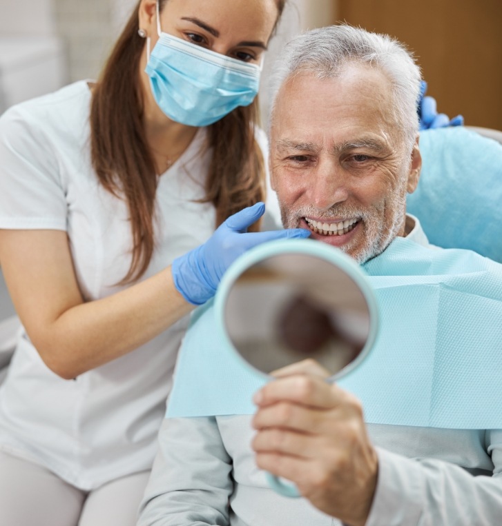 Man smiling while using a mirror in a dental office