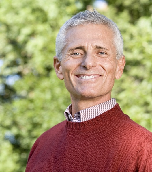 Man in red sweater smiling outdoors