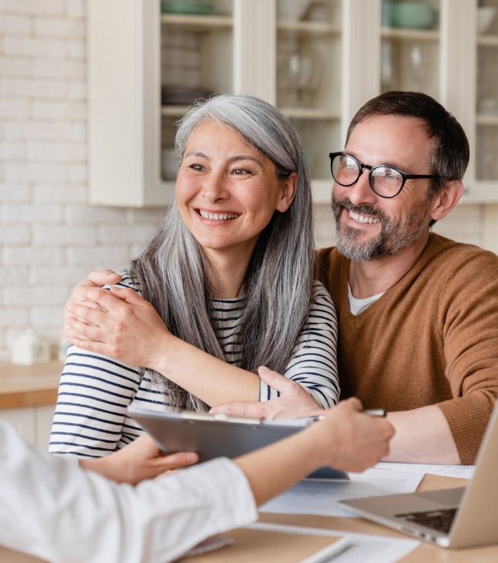 Man and woman smiling at person across desk