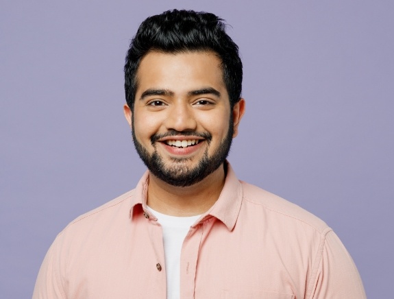 Man smiling against light purple background