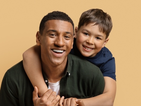 Young boy hugging his father from behind