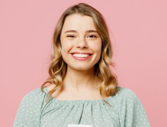 Young woman grinning against pink background