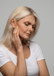 Senior woman holding the side of her jaw in pain