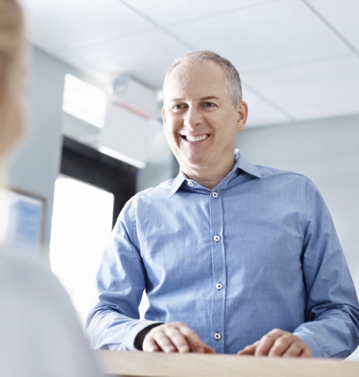 Man smiling at dental office receptionist