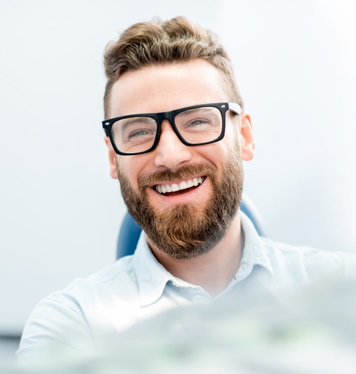 Young man with short beard smiling in dental chair