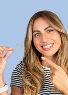 Woman pointing to Invisalign aligner