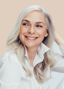 Woman with long gray hair grinning with her hand behind her head