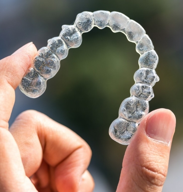 Hand holding an Invisalign clear aligner in Hillsboro