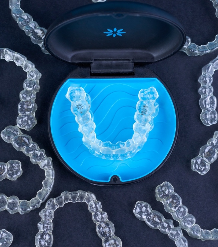 Several Invisalign aligners on desk with one pair in carrying case