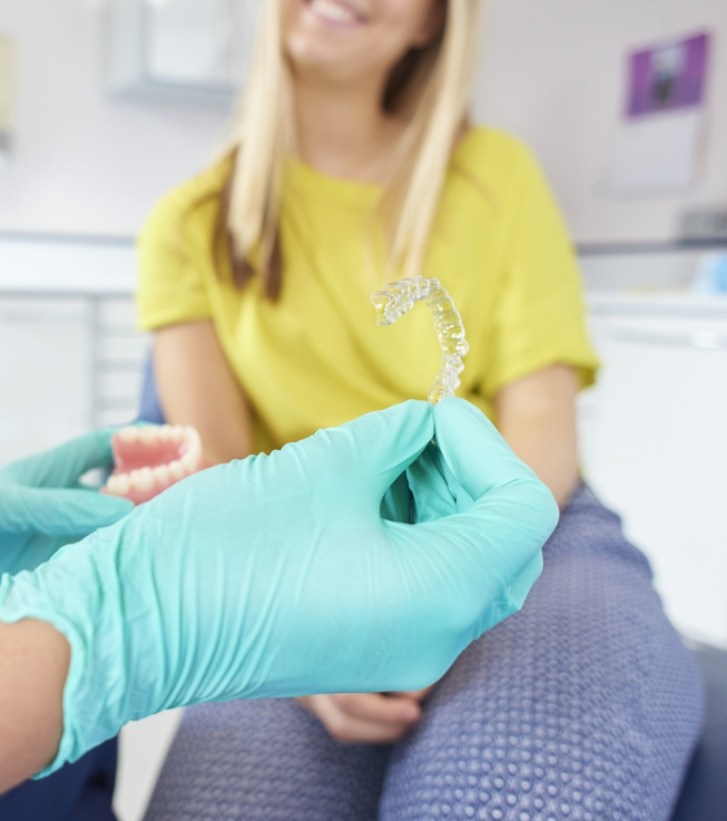 Dentist holding a clear aligner out to a patient