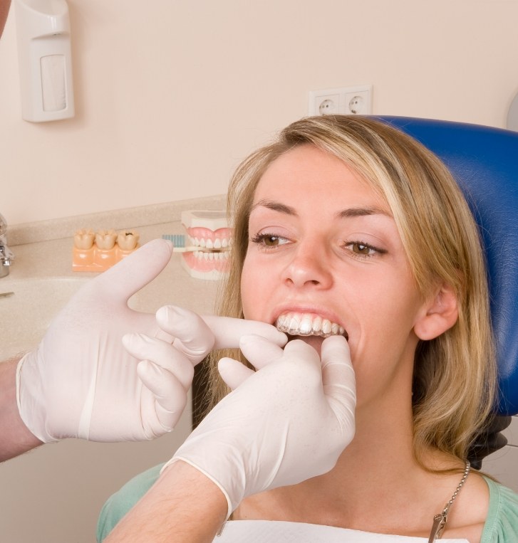 Dentist placing a clear aligner in the mouth of a dental patient