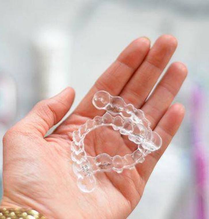 Closeup of person holding two Invisalign aligners