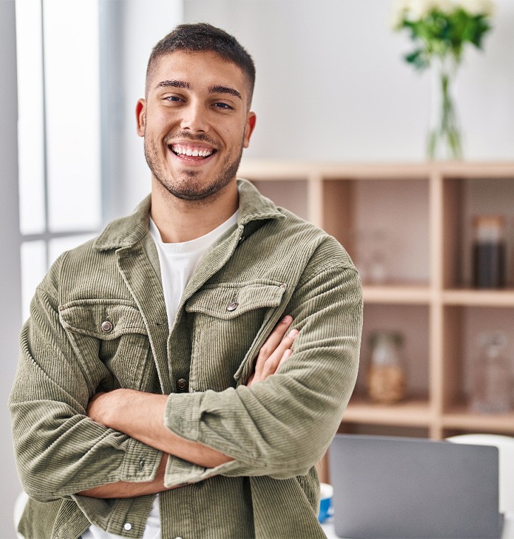 Man in jacket standing in front of shelves and smiling