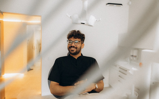Patient with black glasses smiling in treatment chair