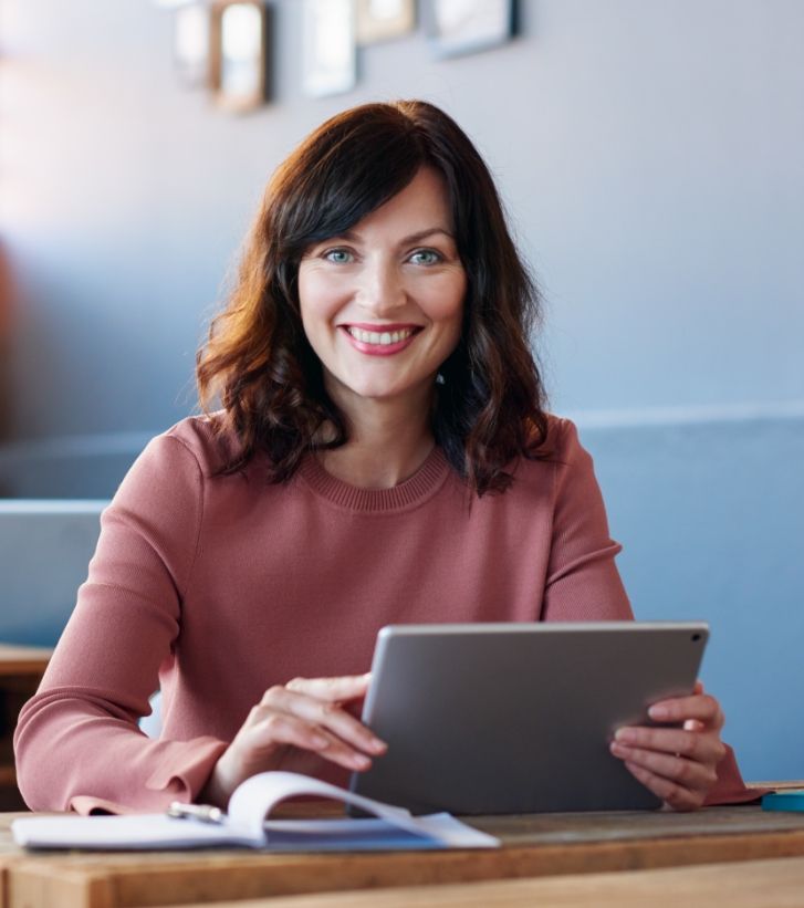 Smiling woman sitting at desk with tablet