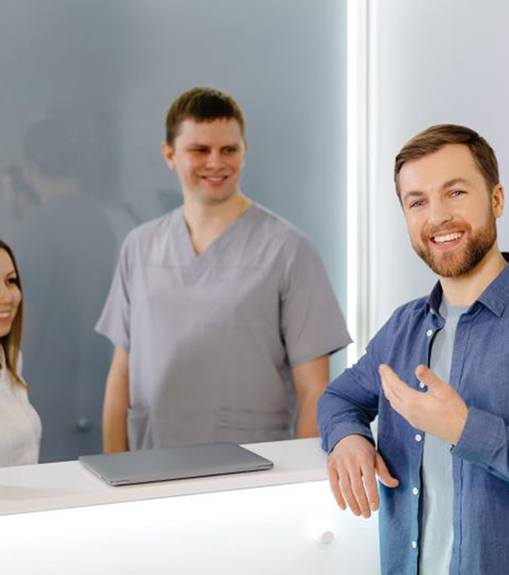 Happy patient standing at dental office front desk