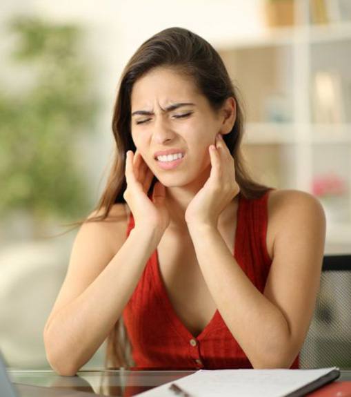 Woman sitting at her computer, suffering because of TMD