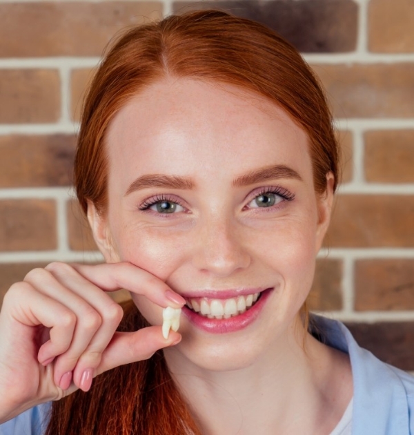 Smiling woman holding an extracted tooth