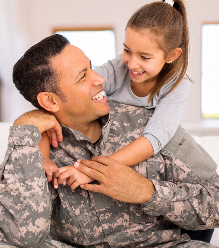 young girl hugging military father