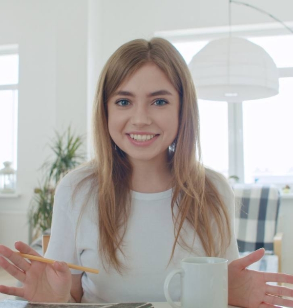 Smiling blonde woman holding pencil while sitting at desk