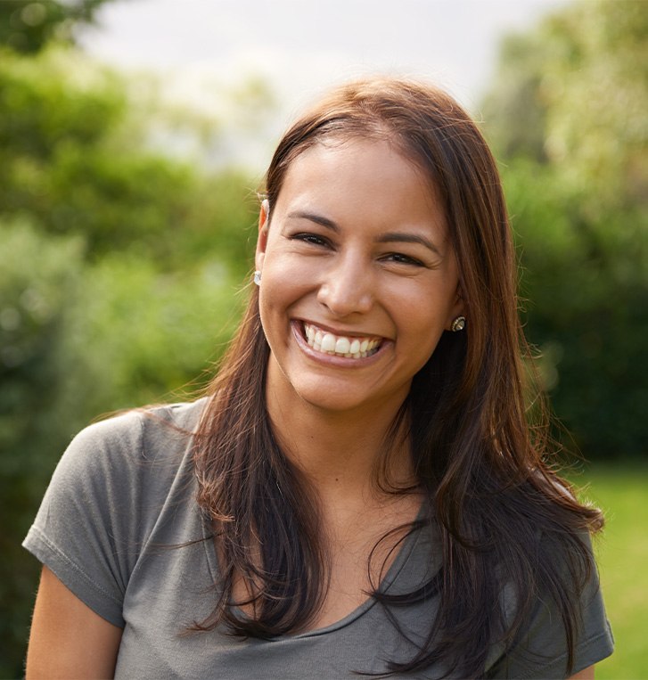 Woman outside among bushes smiling