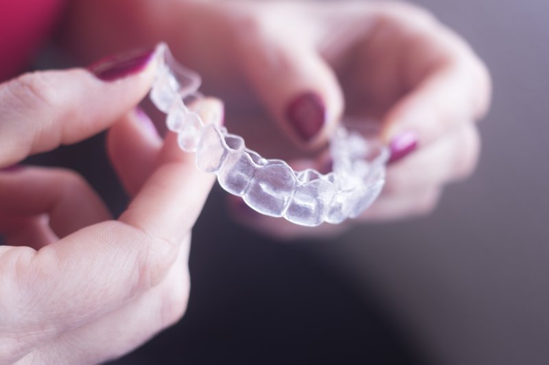 person holding Invisalign clear aligner