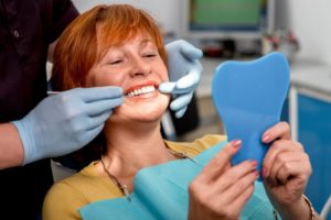 a woman smiling at her dental implants while at the dentist