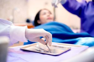 Dentist's hand grabbing instrument with patient blurry in the background