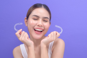 Woman holding Invisalign trays and smiling