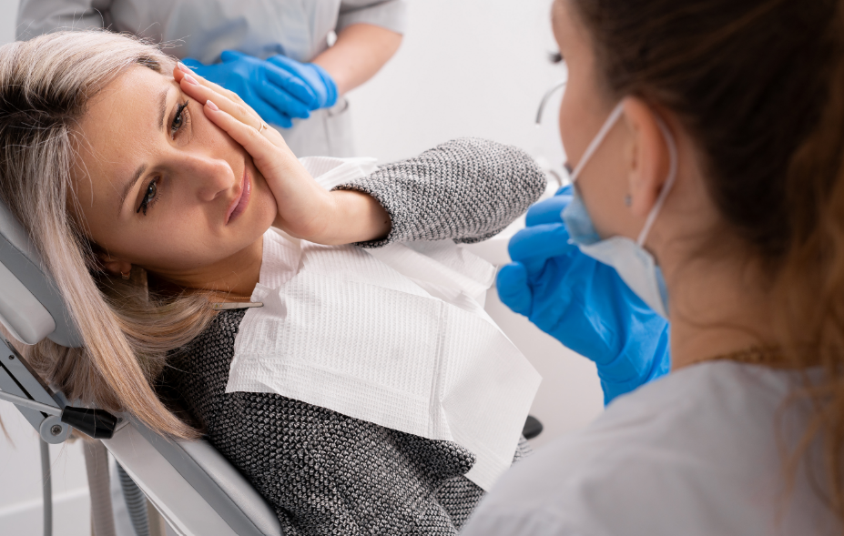 Woman in dental chair clutching jaw